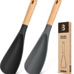 Two Badiano silicone cooking spoons, one black and one grey, with wooden handles, resting on a clean surface.