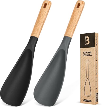 Two Badiano silicone cooking spoons, one black and one grey, with wooden handles, resting on a clean surface.