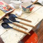 Five midnight blue silicone kitchen utensils with natural acacia wood handles, including a spoon, spoonula, spatula, turner,